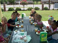 Children sitting down eating at a picnic table outside